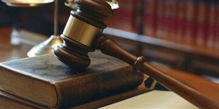 Martelo de juiz, balança da justiça e livros jurídicos sobre mesa de escritório